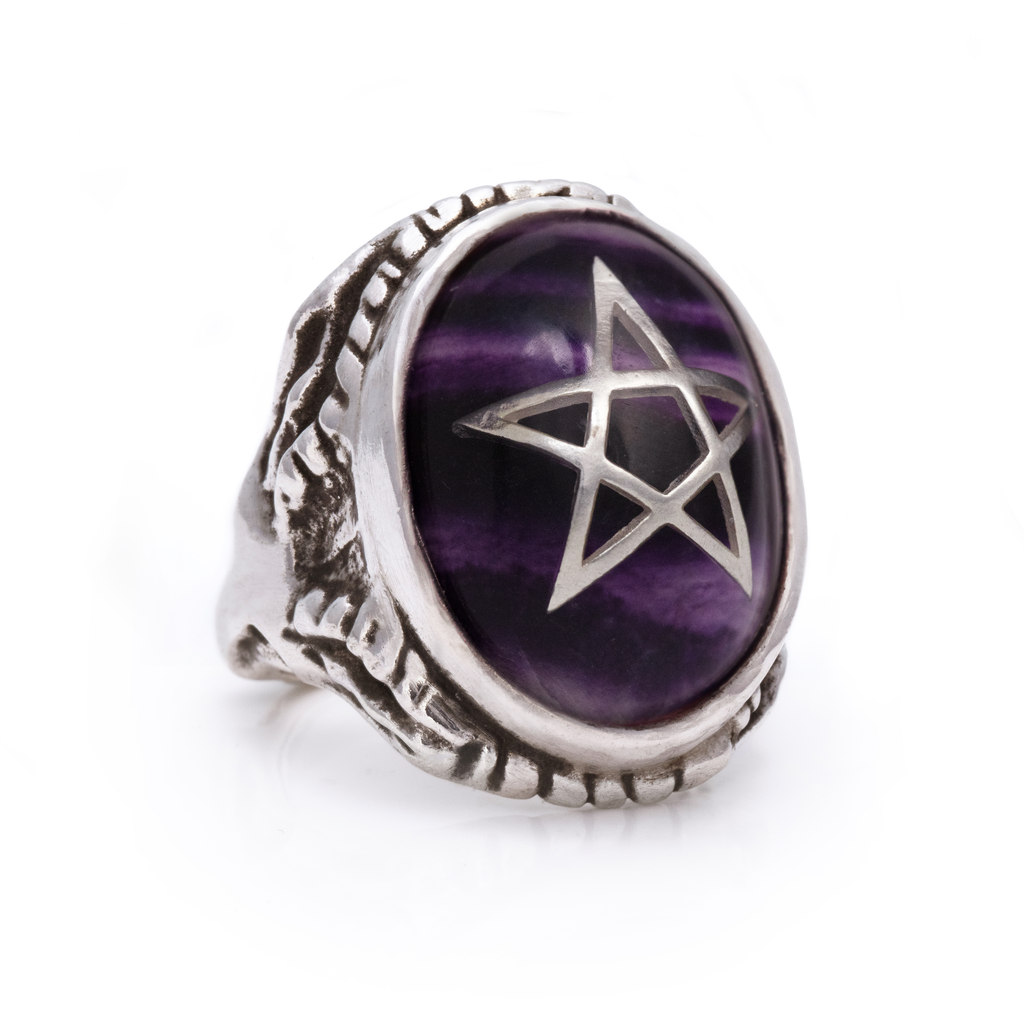 Silver ring with purple stone and star design on a white background